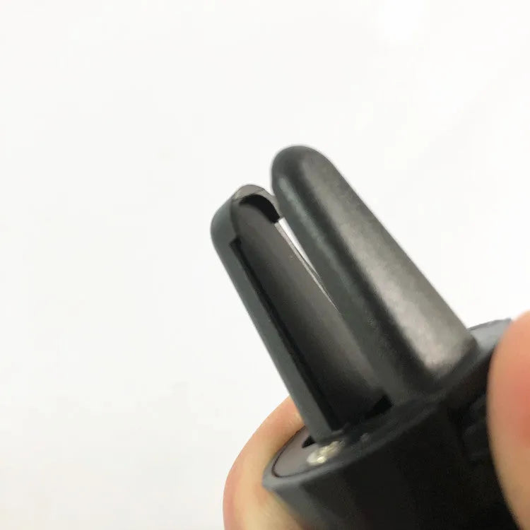 Black car phone holder mounted on vehicle air vent with adjustable clamping arms extended