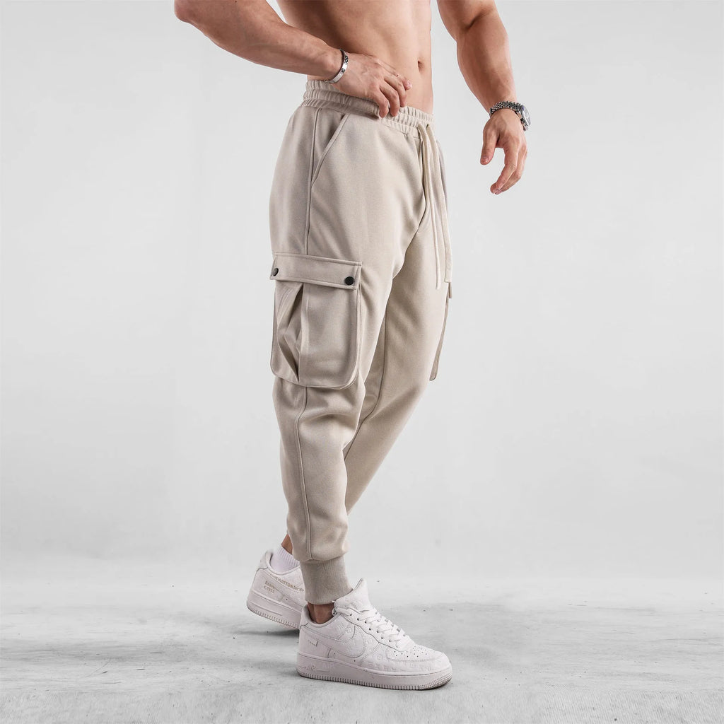 Men's loose fit cotton trousers with ankle-tied cuffs and multiple pockets in a light grey colour.