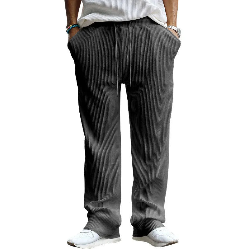 Man wearing casual loose-fit high-waist straight-leg striped trousers in a solid colour.