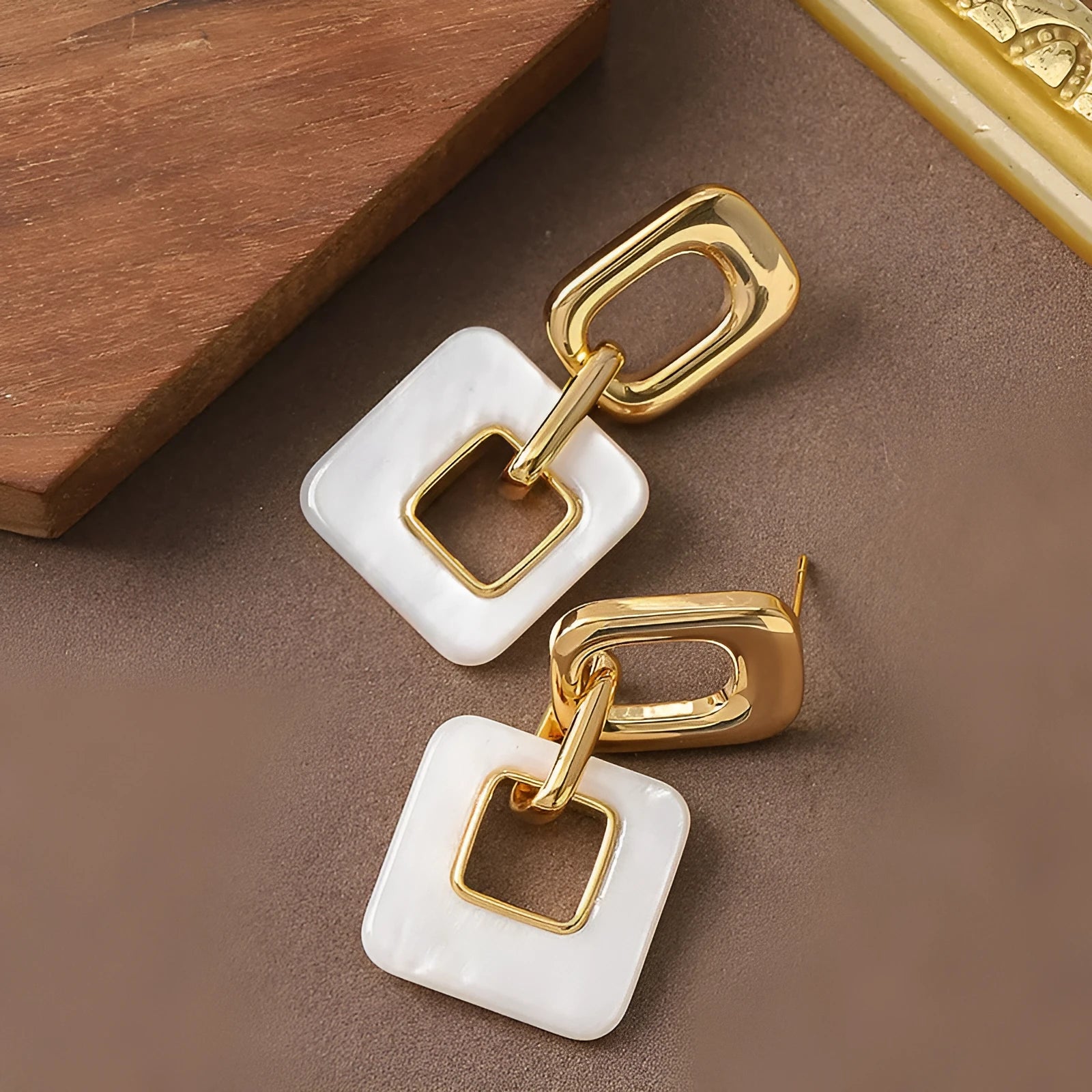 Pair of hollow geometric square earrings with chamfered pattern in silver or black electroplated finish.