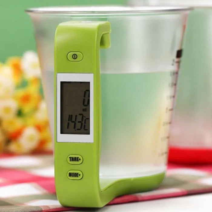 Green electronic kitchen scale measuring cup with digital LCD display on handle.