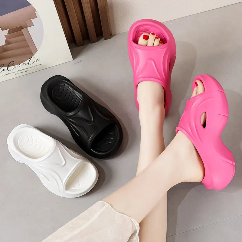 Women's white thick-soled EVA slippers with rounded toe on a sandy beach.