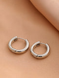 Smooth geometric hollow stud earrings in gold and silver colour options on a neutral background