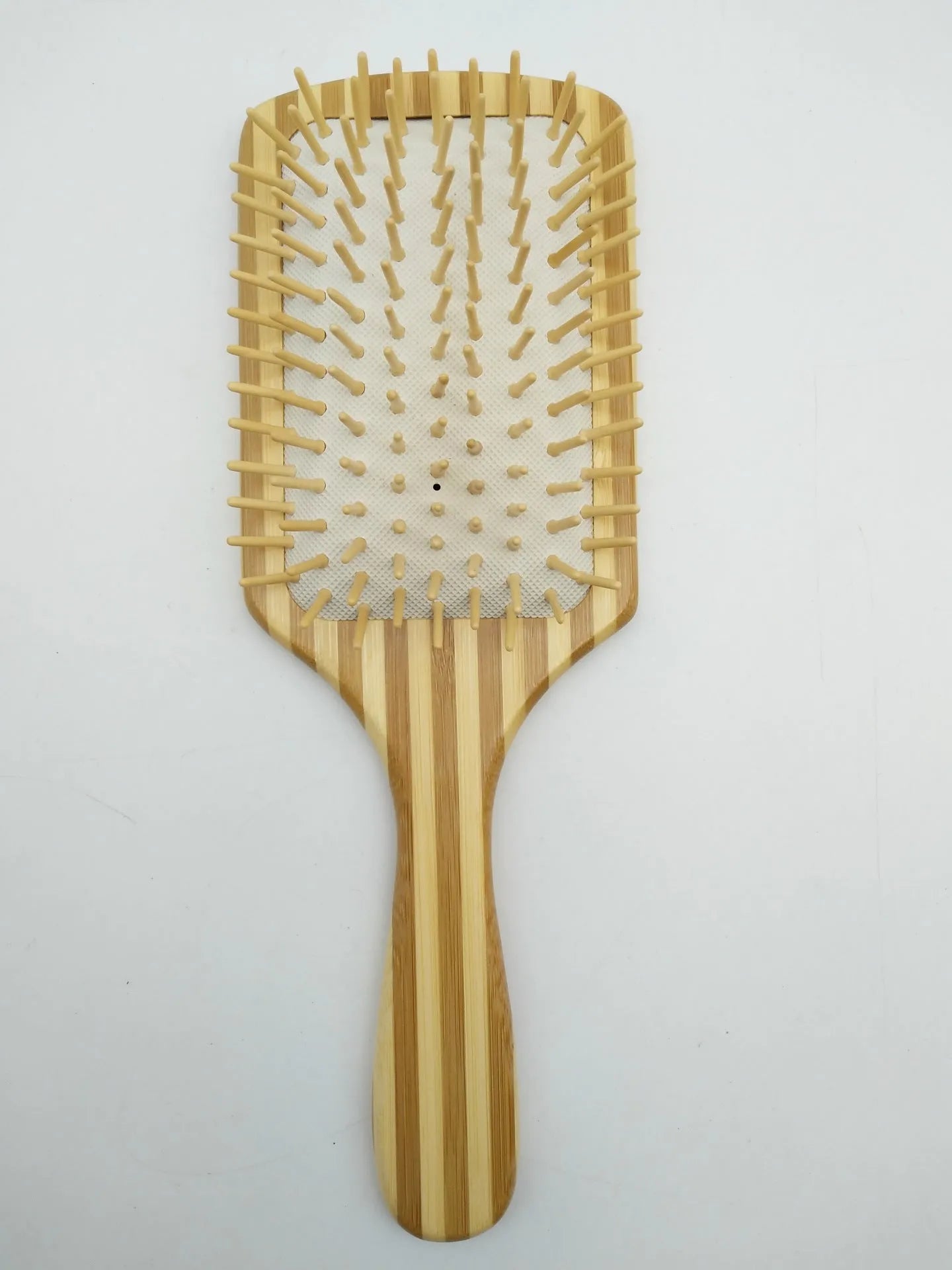 Natural bamboo scalp massage comb with round nylon teeth and rubber pad on neutral background