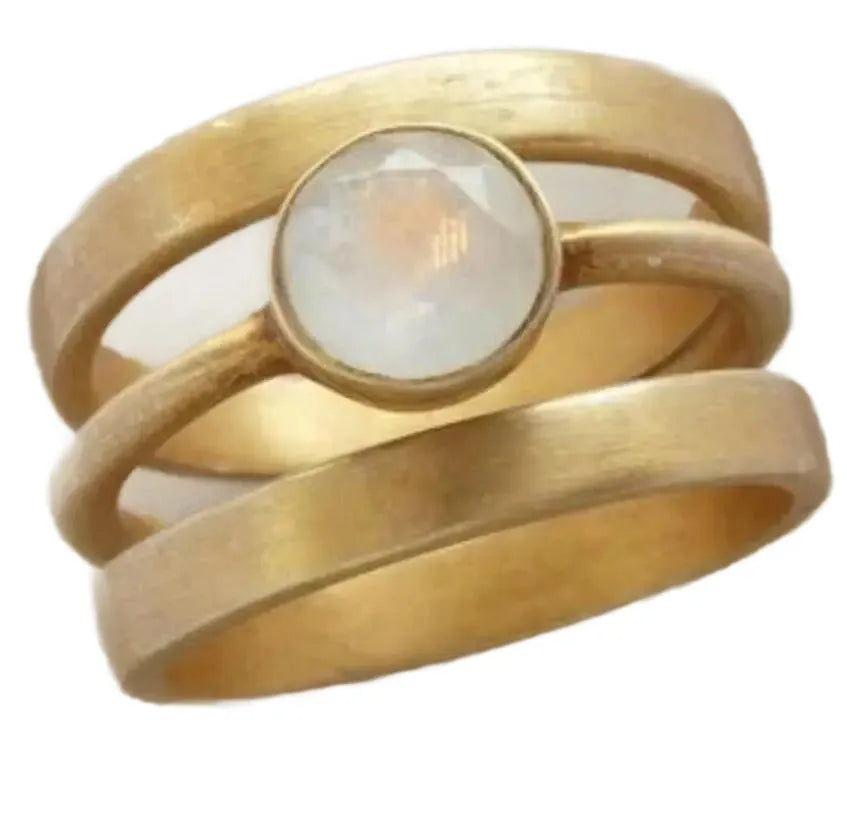 Gold geometric hollow ring with a small white chalcedony stone, on a plain background.