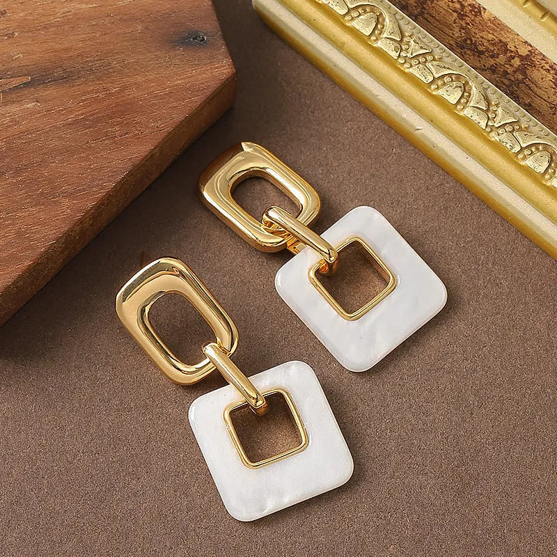 Pair of hollow geometric square earrings with chamfered pattern in silver or black electroplated finish.