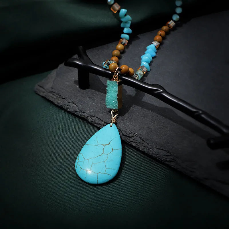 Turquoise blue water drop pendant necklace with geometric shapes on a long ball bead chain.