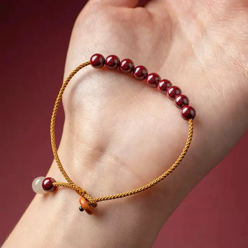 Close-up of a hand-woven geometric bracelet made from cinnabar and Hetian jade stones.