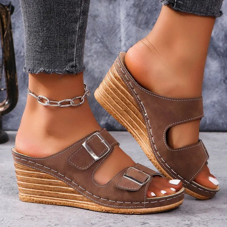 Women's creamy-white beach slippers with a decorative wedge buckle on the strap.