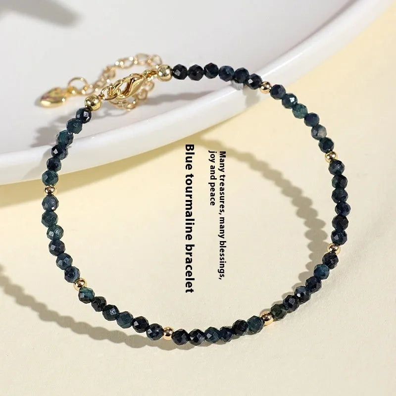 3mm blue tourmaline cut bead bracelet with spacer beads on a wrist