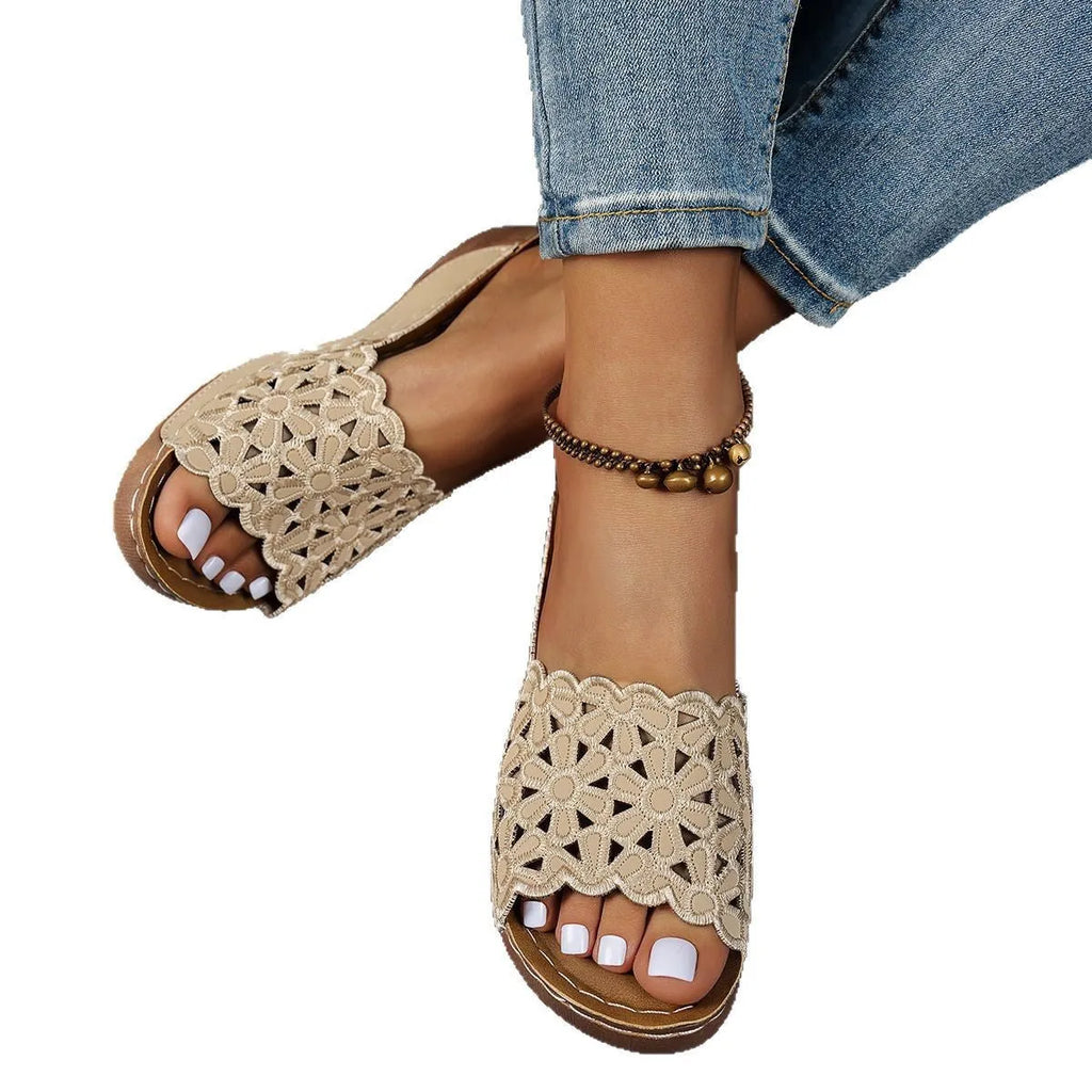 Women's black beach slippers with flower cutout design on the PVC upper and a rubber wedge sole.