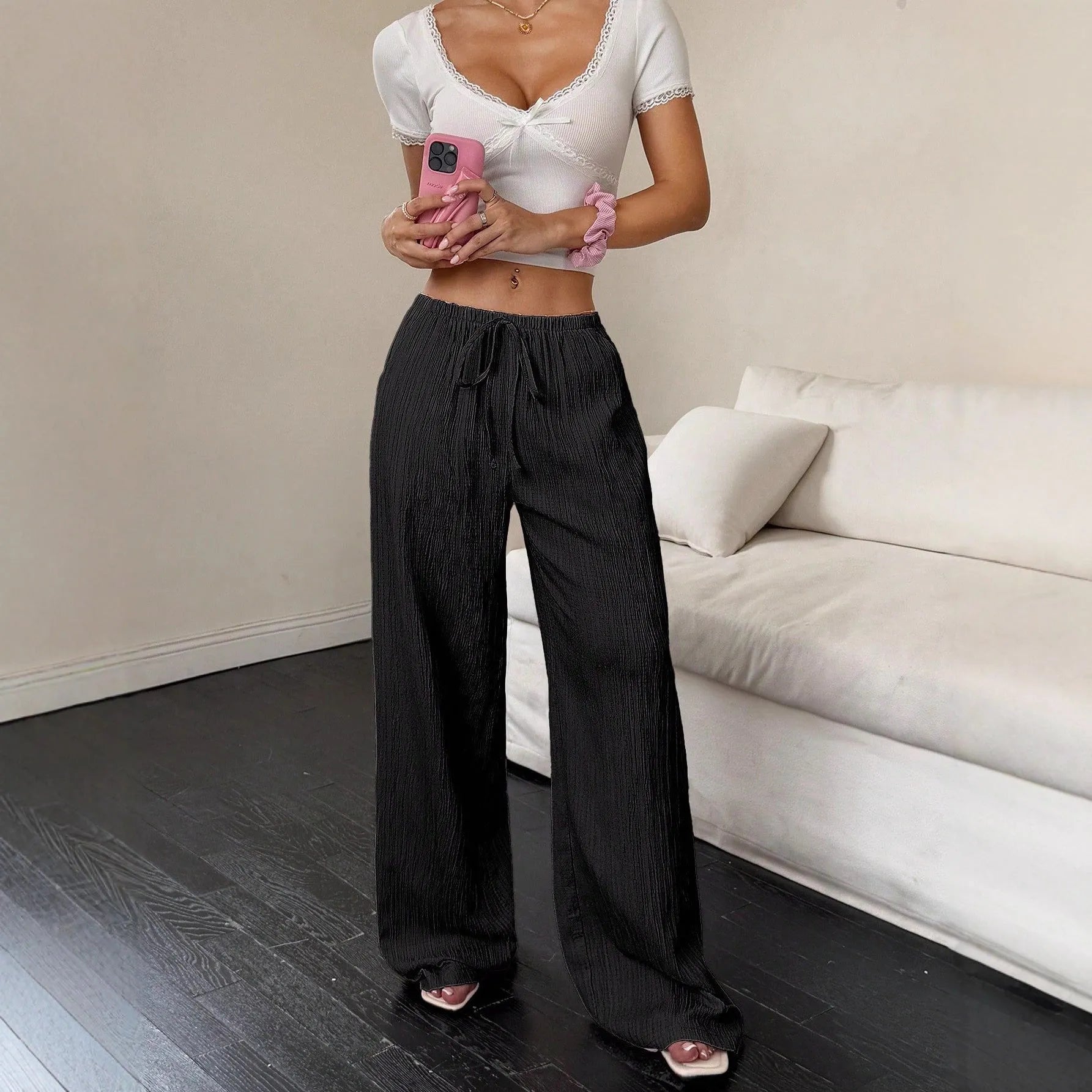 Women's black wide-leg trousers with a white lace-up detail at the mid waist on a hanger.
