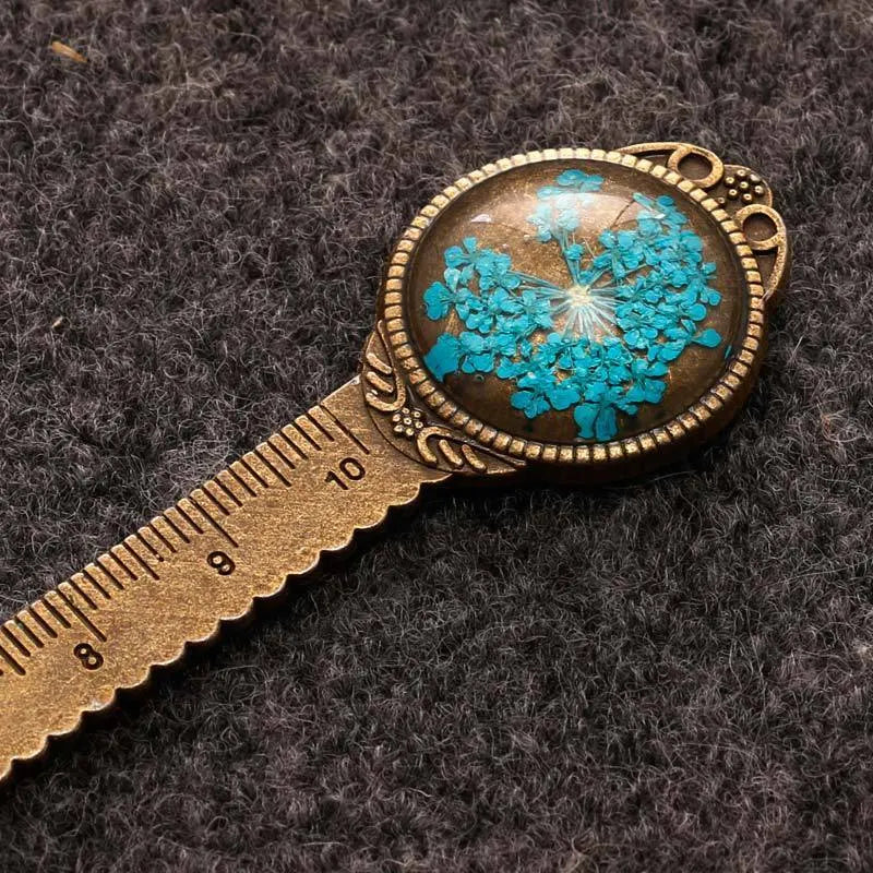 Handmade dried flower bookmark with lace flowers, daffodils, and clover, measuring 12cm long, on a book.