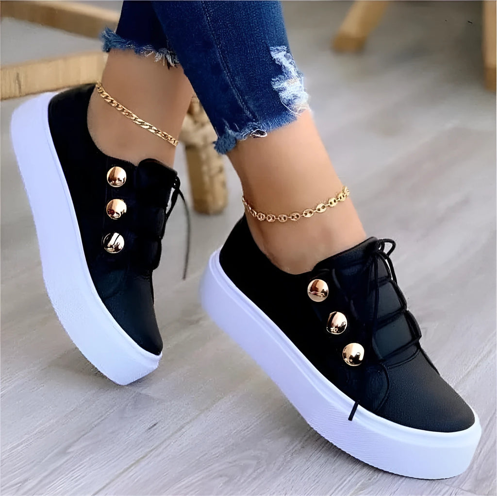 Women's white lace-up flats sneakers with silver rivet details on the low upper and a round toe.