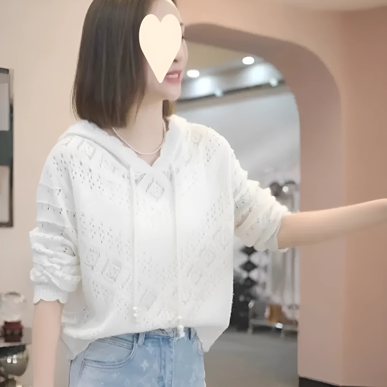 Women's white crochet knit hooded longsuit undershirt on a hanger, showing long sleeves and textured fabric.