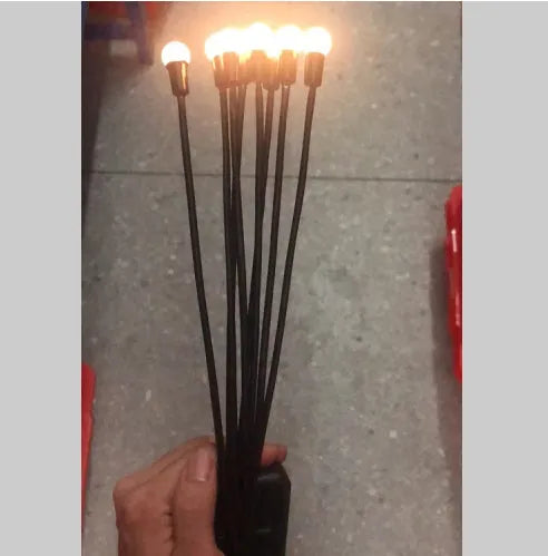 Solar-powered LED firefly lawn light with ground stake inserted in grass