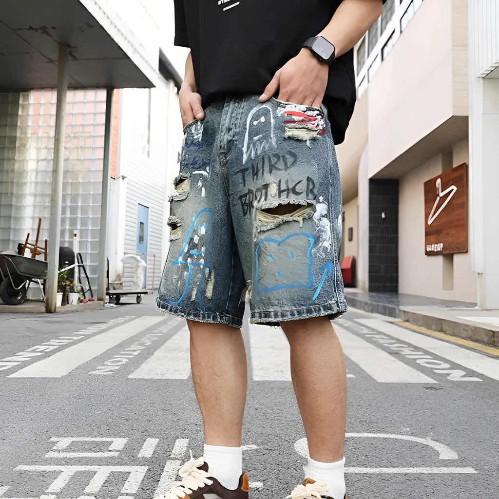Blue men's ripped denim shorts with graffiti details and straight-leg cut
