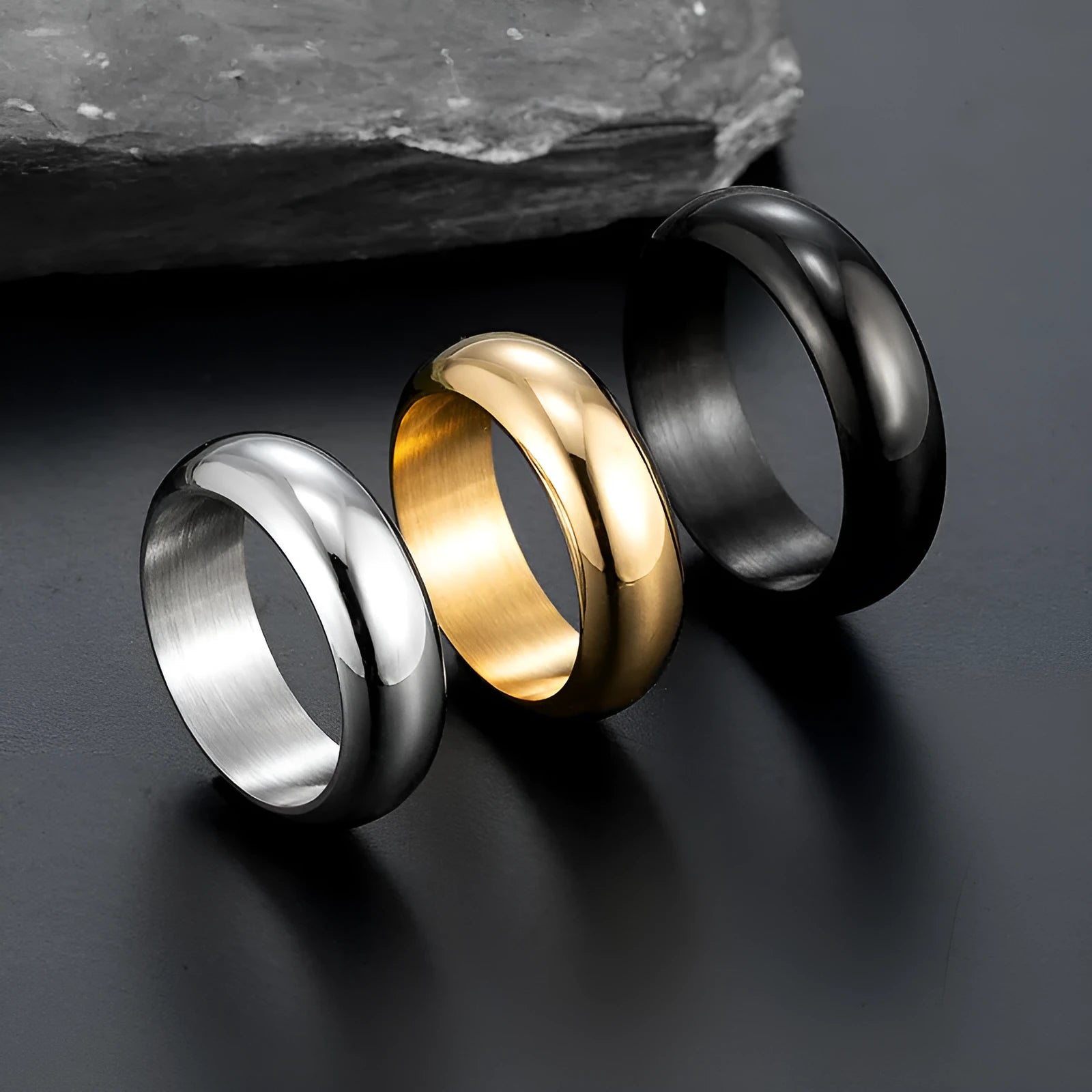 Glossy electroplated titanium steel ring in gold, black, and steel colours on a grey background.