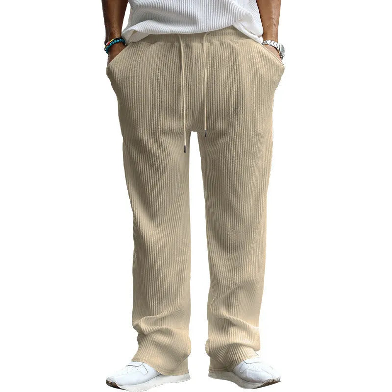 Man wearing casual loose-fit high-waist straight-leg striped trousers in a solid colour.