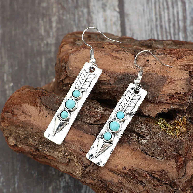 Silver long drop earrings with turquoise inlay and a geometric shape.