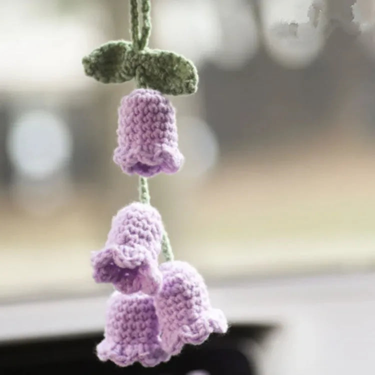 Green and white crochet wool car plant decoration with hanging rope on car dashboard