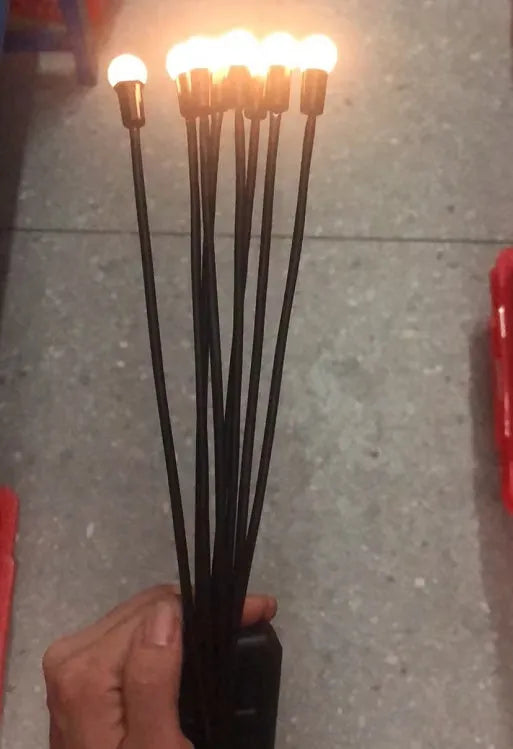 Solar-powered LED firefly lawn light with ground stake inserted in grass
