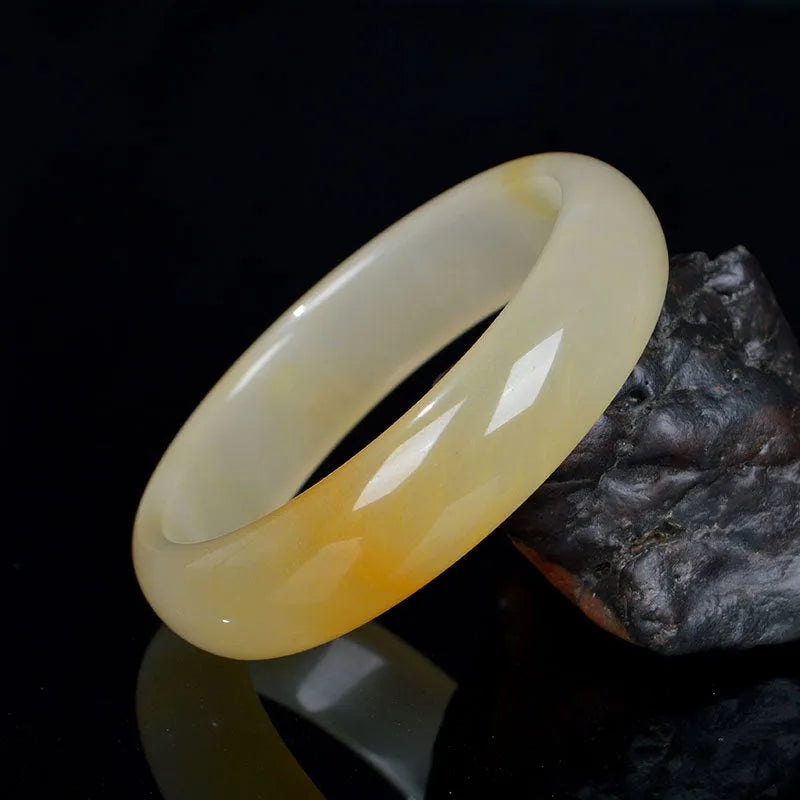 Natural light green jade bracelet in Chinese style, shown on a wrist, with a polished surface.