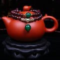Close-up of a deep red natural garnet bracelet with 7mm beads, a golden toad charm, and a double ring clasp.