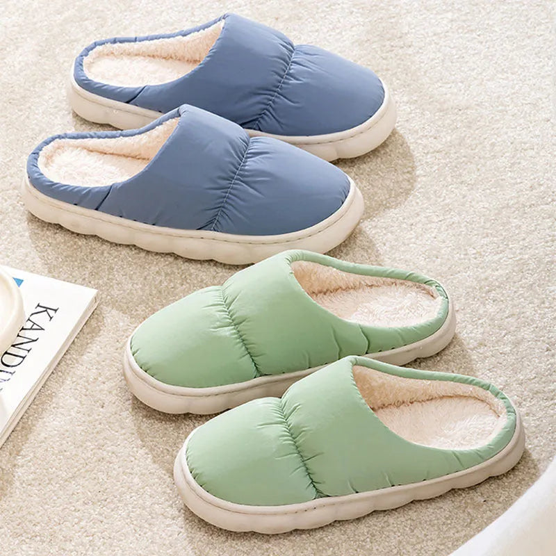 Blue down cotton indoor slippers with thick rubber sole and plush lining on a wooden floor.
