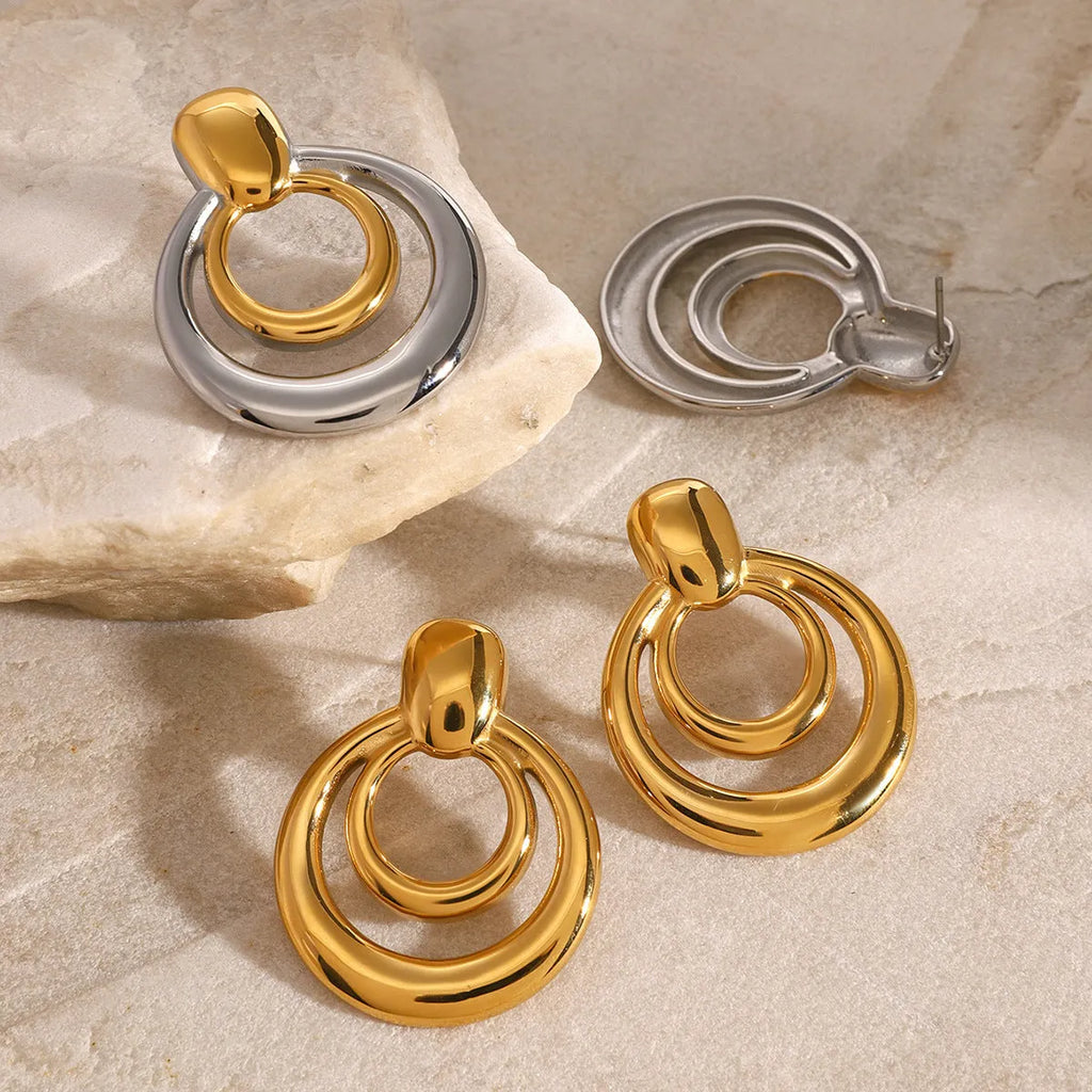 Golden round double layer hollow stud earrings with geometric design on white background