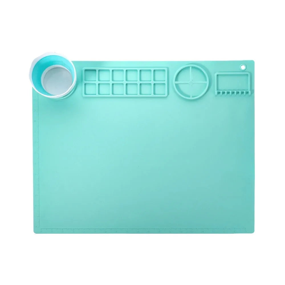 Light blue silicone painting mat with two mixing bowls, measuring 50cm by 40cm on a wooden table.
