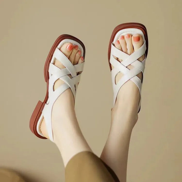 Women's glossy patent leather sandals with a square toe and flat low heel in black.