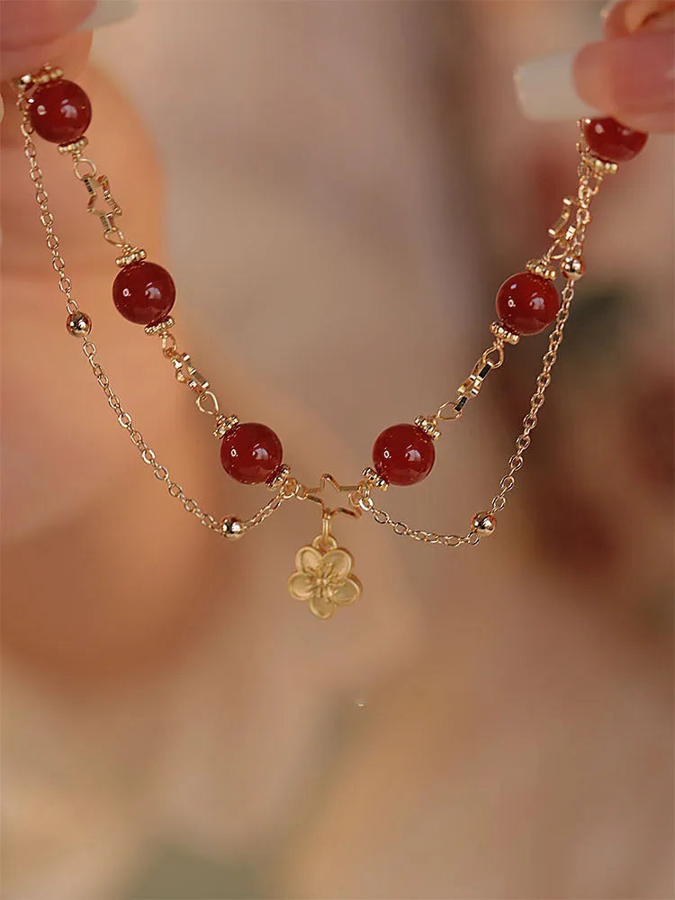 Red agate double layer women's bracelet with peach blossom design on adjustable string.