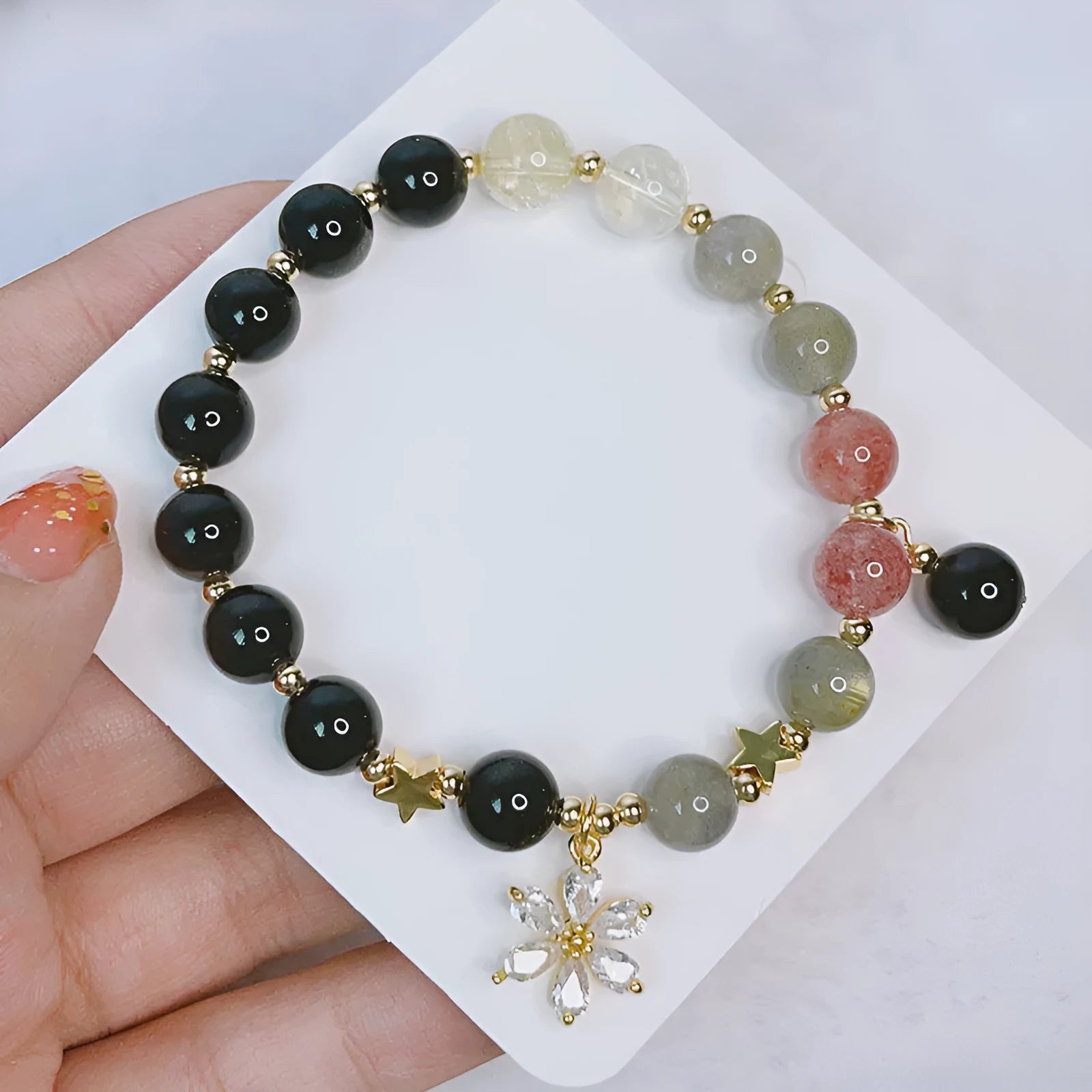 Adjustable silver stone bracelet for women with choice of flower, love, or star charm on a white background.