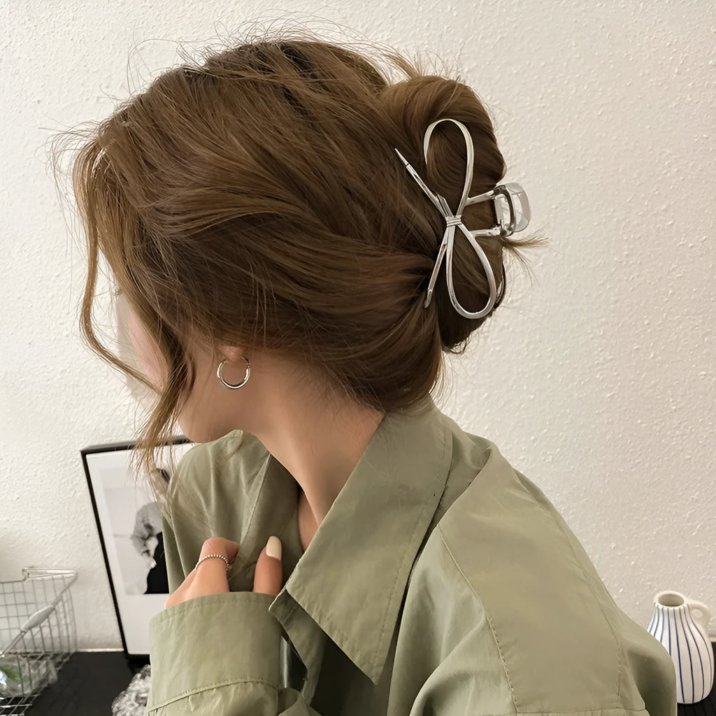 A silver and a gold alloy hair barrette with a prominent bow design.