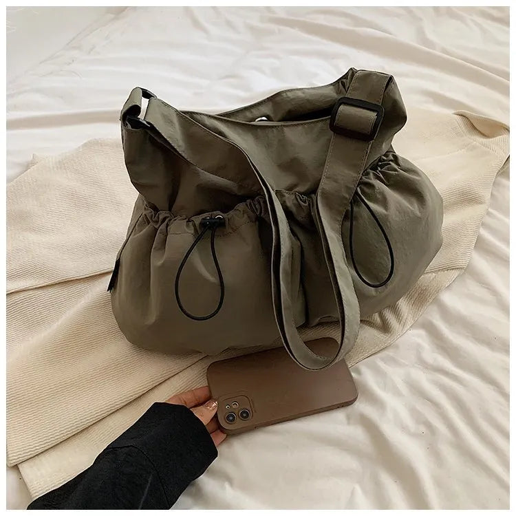 Green ultra-light pleated crossbody student bag showing folding design and split outer pocket