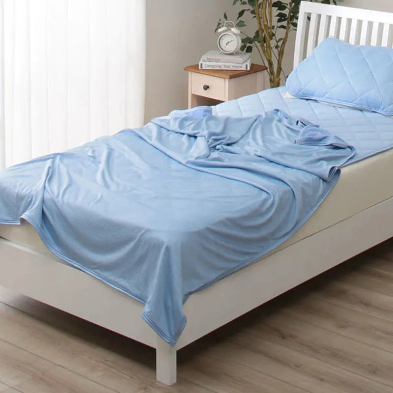 Blue and grey cooling blanket with Japanese Q-Max fibres on a bed.