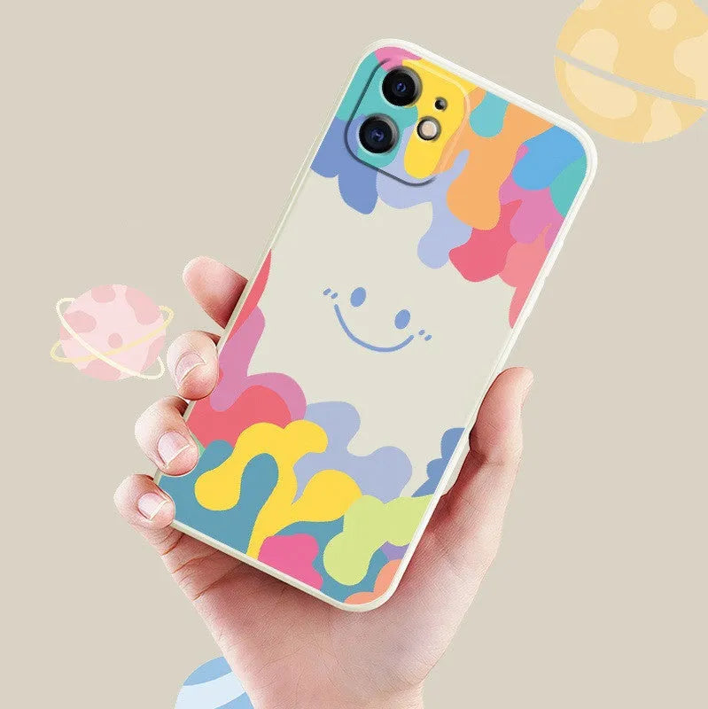 White and black silicone iPhone cases featuring a large rainbow smiley face design, shown with attached lanyards.