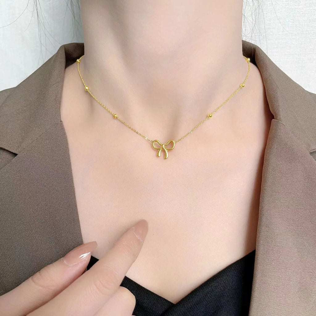 Gold electroplated bow necklace on cross chain with adjustable length