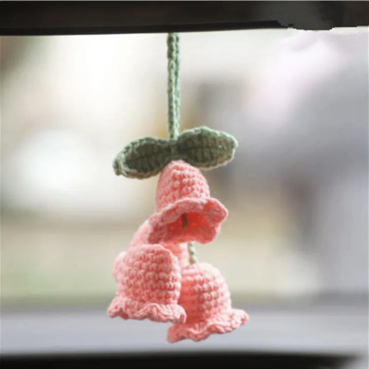 Green and white crochet wool car plant decoration with hanging rope on car dashboard