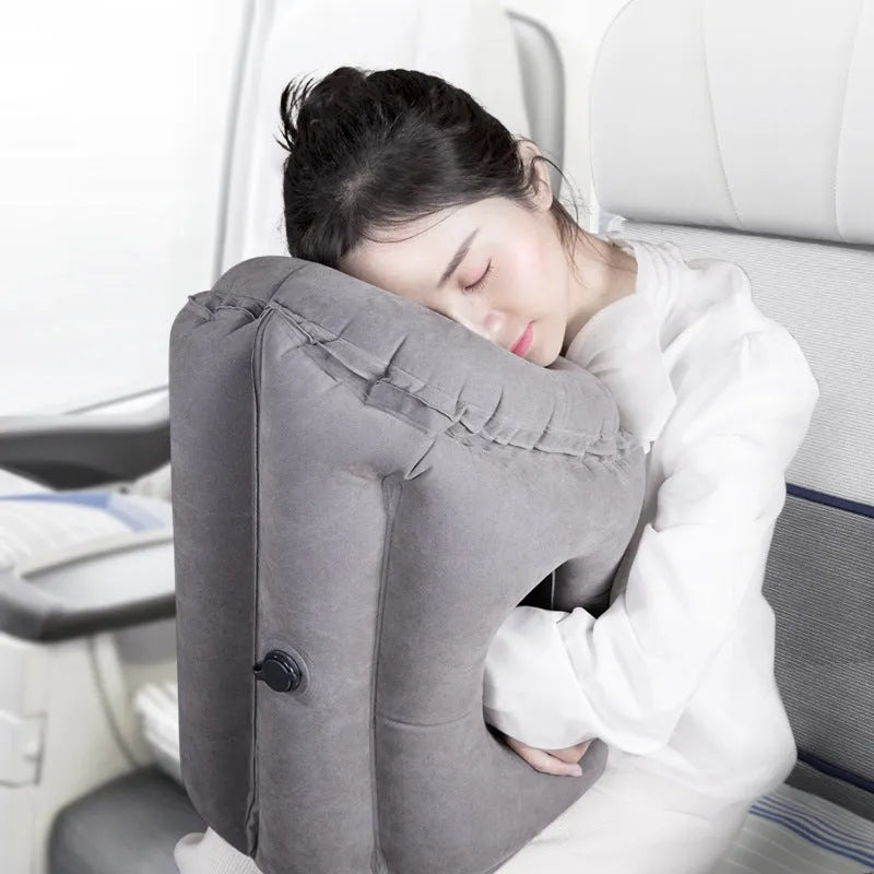 Grey inflatable sleeping pillow with flocking surface deflated on surface with storage bag