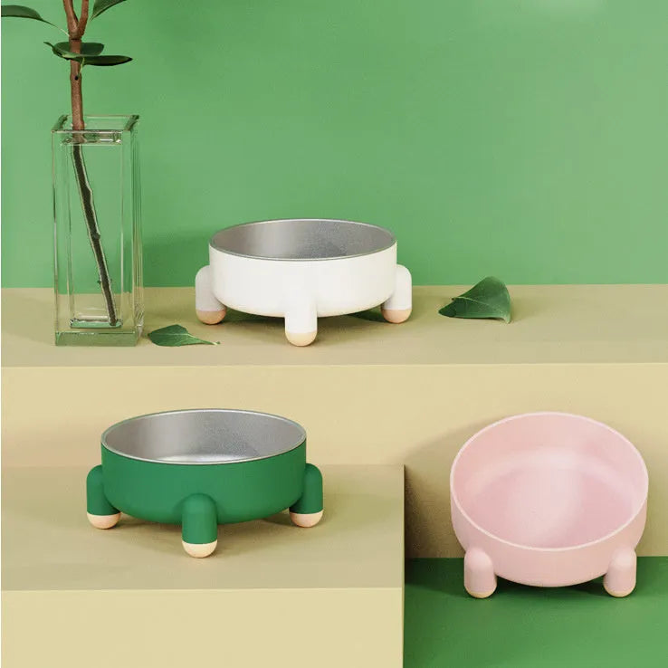 Green stainless steel pet bowl with a high foot and non-slip base on a kitchen floor.