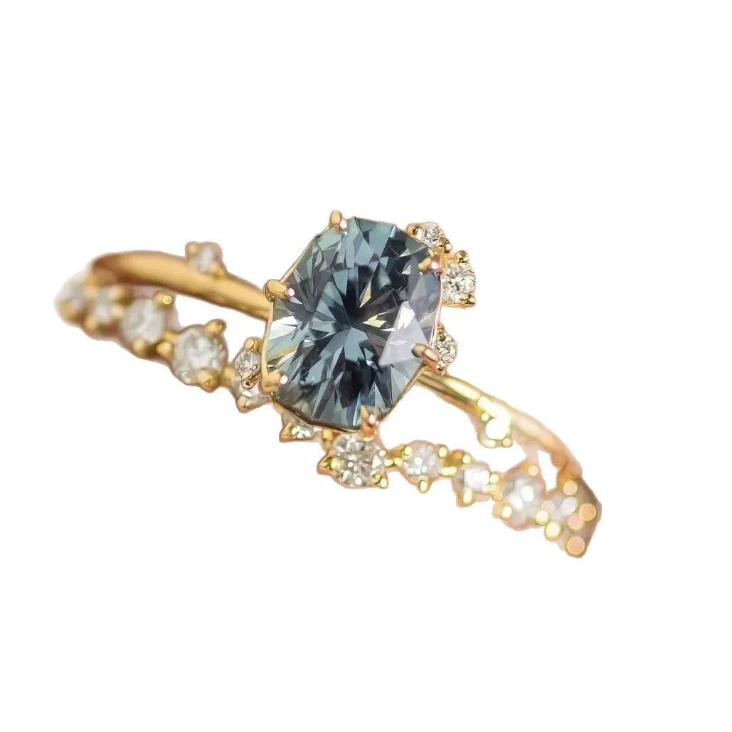 Gold-plated women's ring with green zircon stones and floral engraving on a white background.