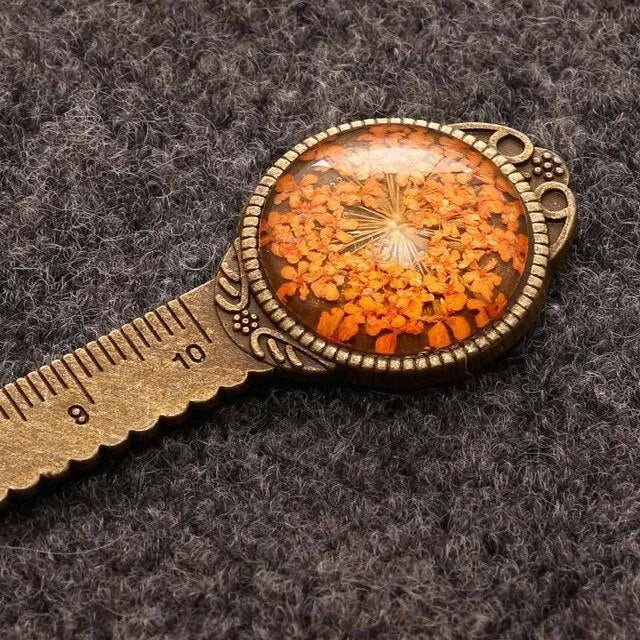 Handmade dried flower bookmark with lace flowers, daffodils, and clover, measuring 12cm long, on a book.