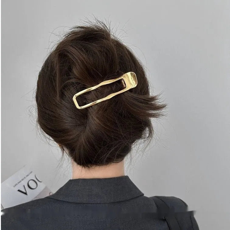 Golden zinc alloy hair barrette in an arc shape on a white background