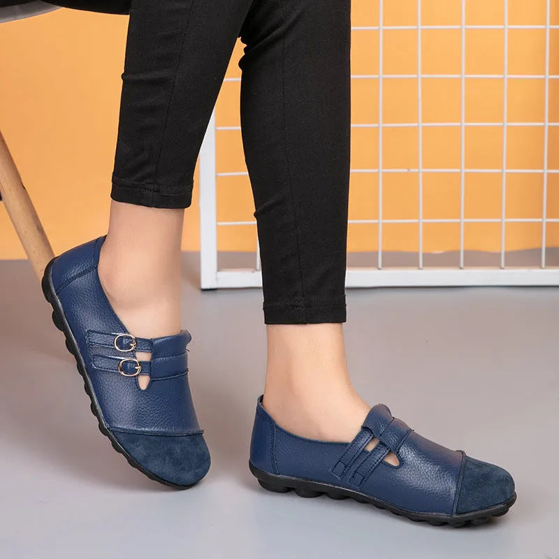 A pair of casual black flat shoes with a round toe, Velcro strap, and cow split leather upper.
