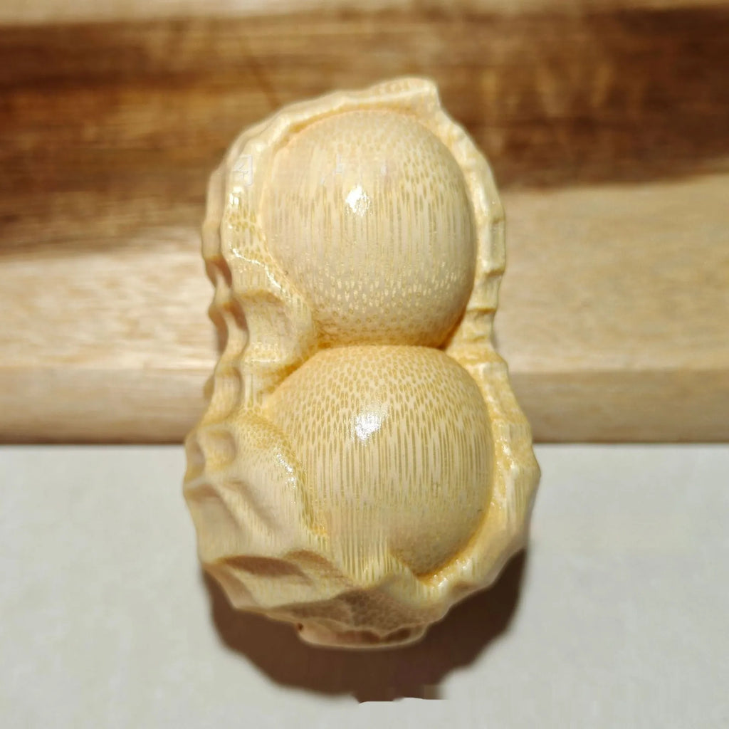Solid natural bamboo carved peanut ornament with modern simple design on a wooden surface.