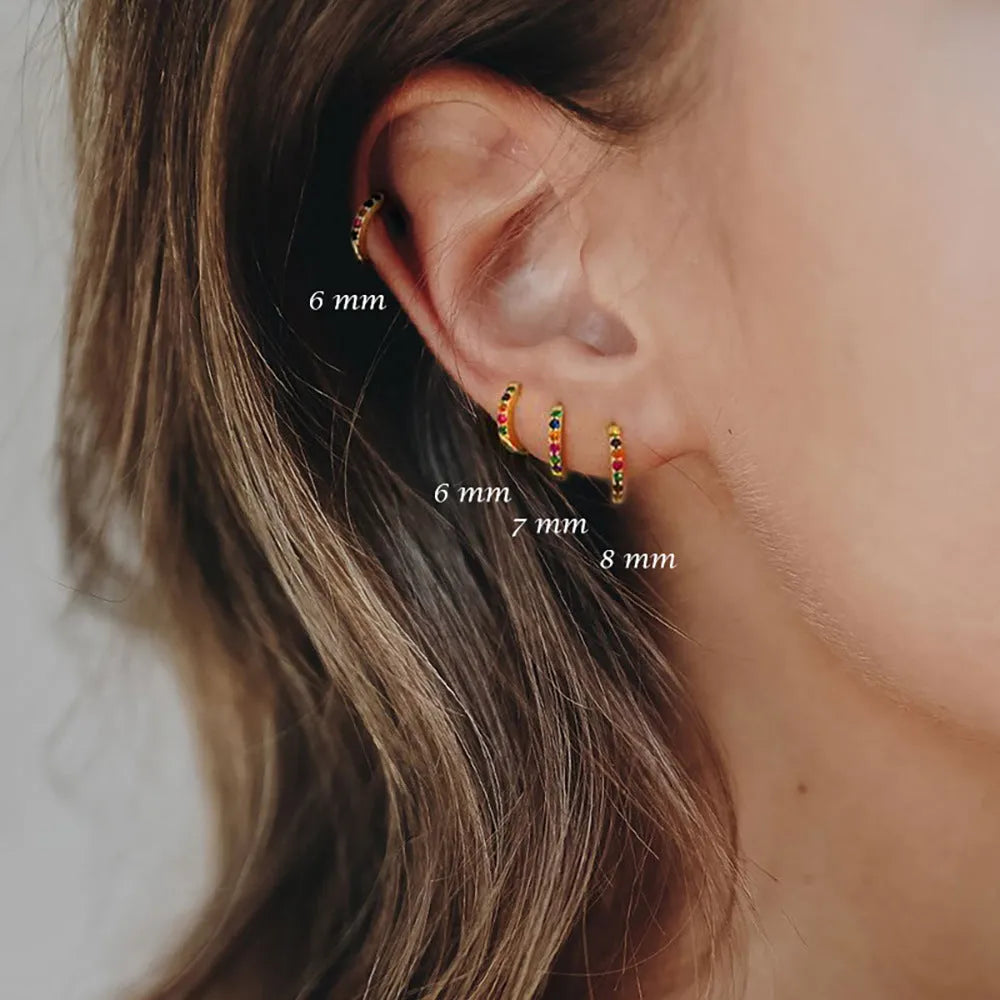 A pair of round gold-coloured stud earrings with a geometric perforated design and central zircon stone.