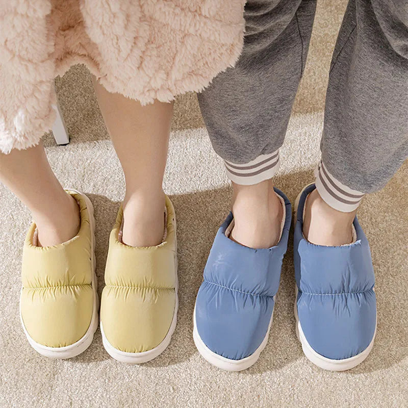 Blue down cotton indoor slippers with thick rubber sole and plush lining on a wooden floor.