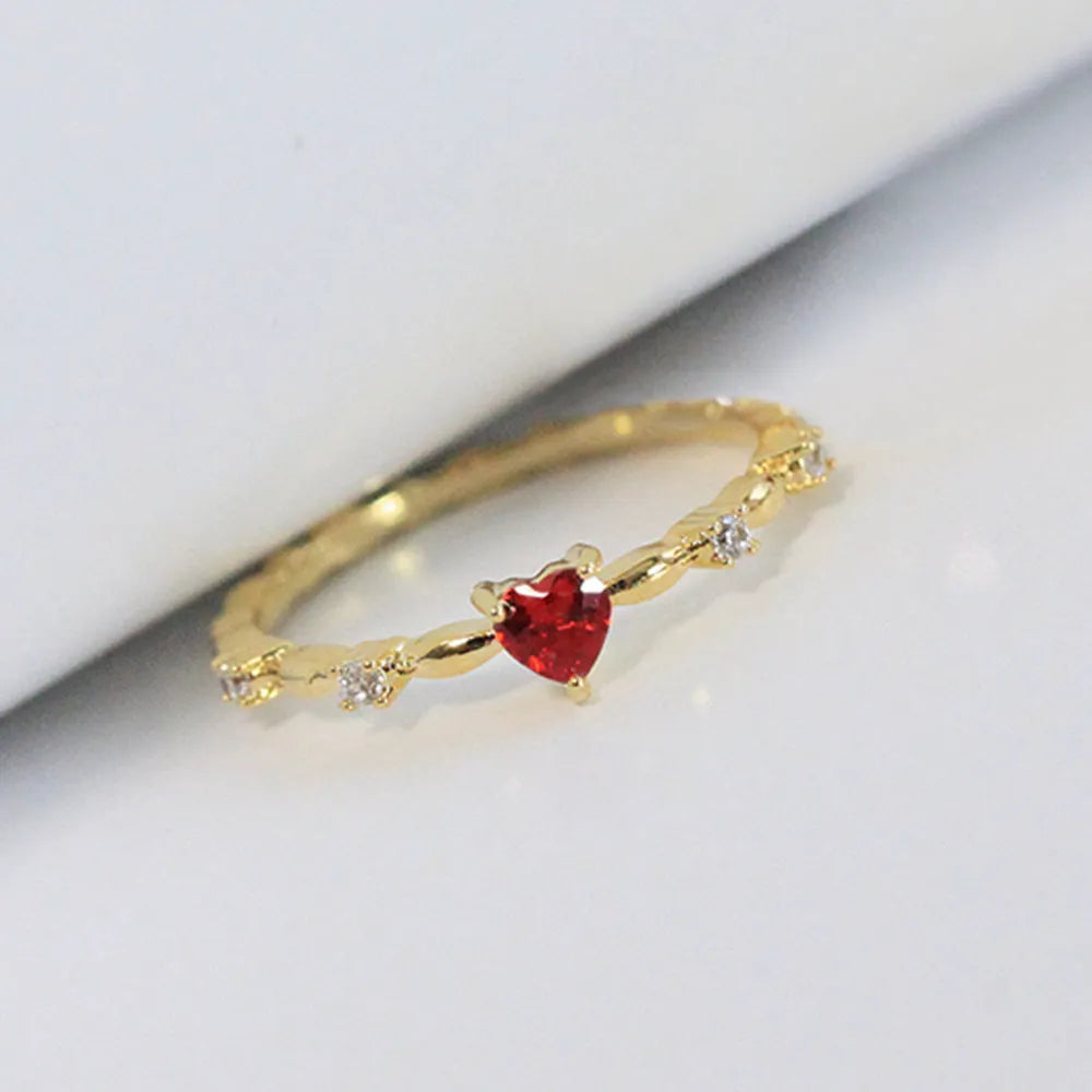 Gold tone peach heart ring with zircon stone centre on finger